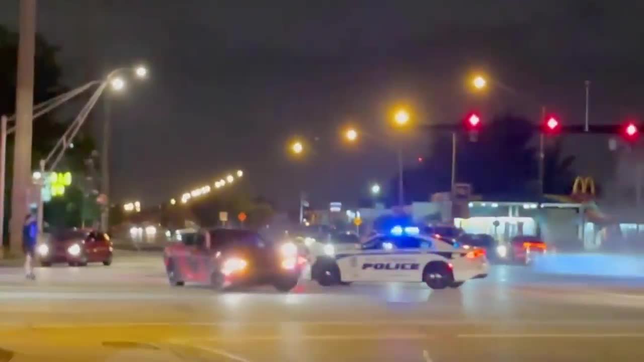 Car driver does doughnut in the middle of intersection in front of patrol car