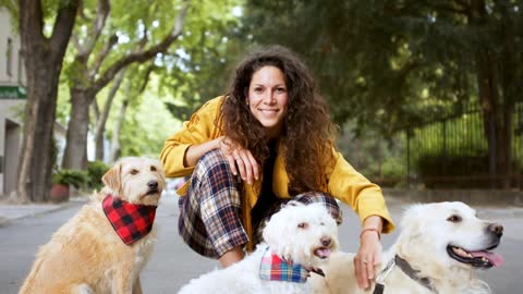 Front view of happy woman with three pet dogs outdoors in city, resting