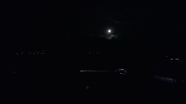 The Beautiful full moon and a car passing on the road