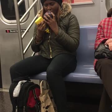 Woman eats purple cabbage with mustard on subway train