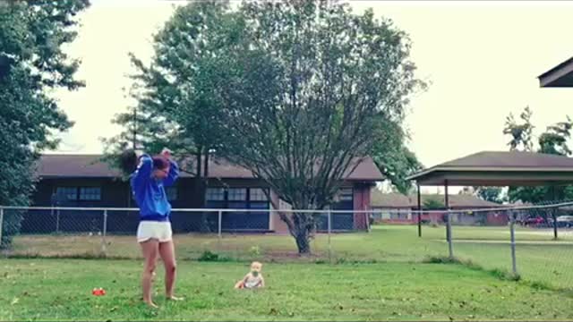 Baby laughs at dog playing with a stick