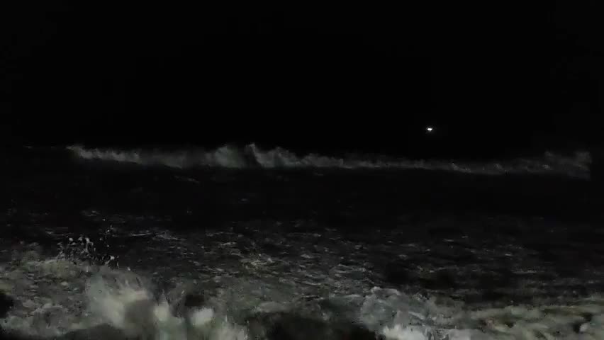 Waves crashing coolly on the breakwater at night