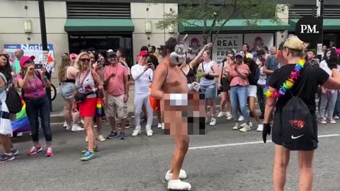 A naked man in a Bugs Bunny mask hops down the street during the Toronto Pride Parade