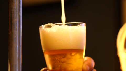 Bartender serving beer from a tap looking down at his hands