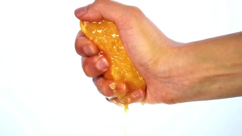 Hand of a person squeezing an orange on a light background