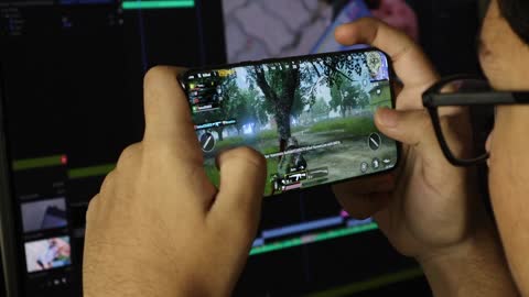 A Young Man Playing A Mobile Game