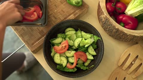 Close Up of Female Hands Adding Sliced Tomato to Salad Bowl