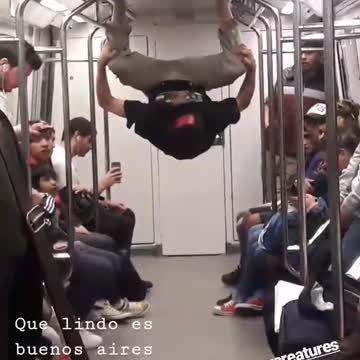 Guy hanging by feet in subway dancing upsides down hands