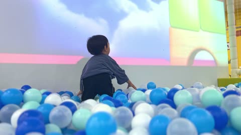 a child playing with a ball in the ball pit