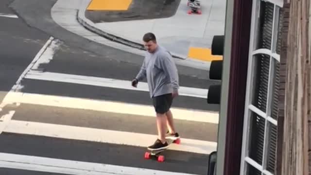 Big guy grey shirt skateboards across street crossing walk