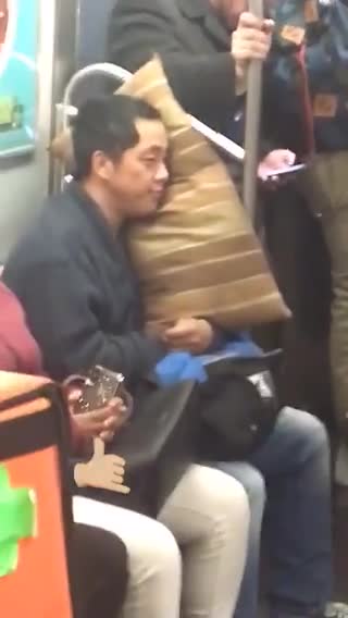 Man sleeps with brown pillow on subway