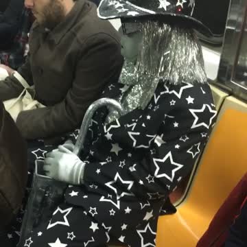 Woman in black and silver star tuxedo on subway train