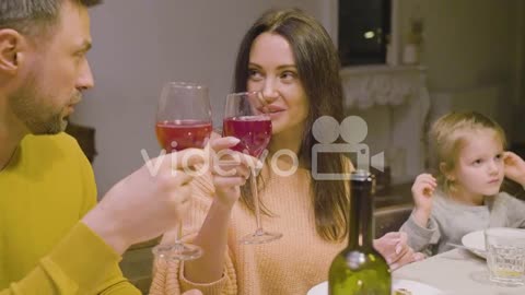 Husband And Wife Talking And Toasting During A Family Dinner Sitting At Table At Home