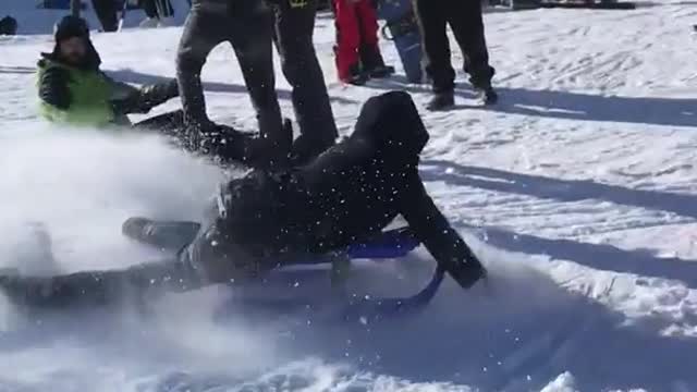 Boy on sled ramps into pile of blue orange objects