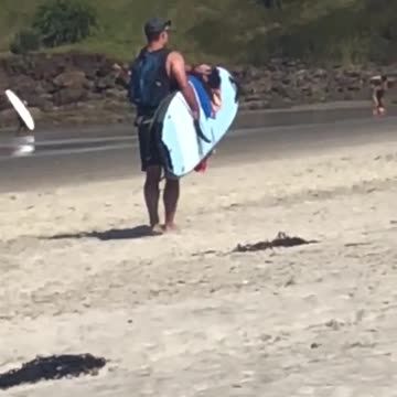 Guy with backpack puts towel on surfboard