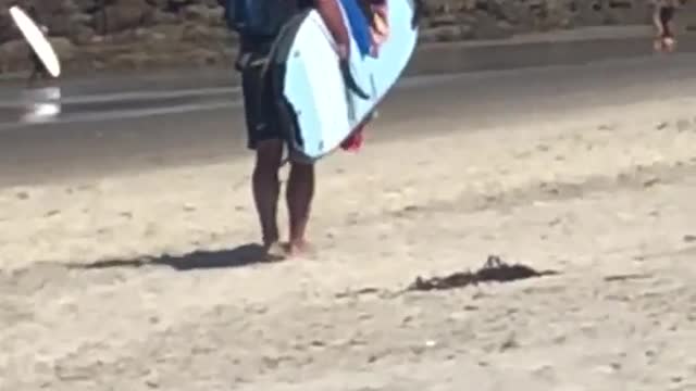 Guy with backpack puts towel on surfboard