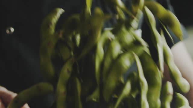 A Man Flipping Cooked Soy Bean Pod In A Cooking Pan