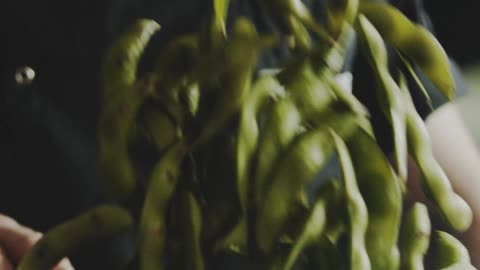 A Man Flipping Cooked Soy Bean Pod In A Cooking Pan