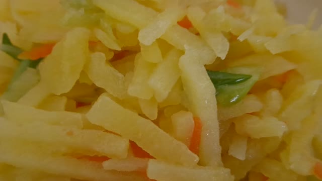 Stir-fried potatoes with carrots and green onions.