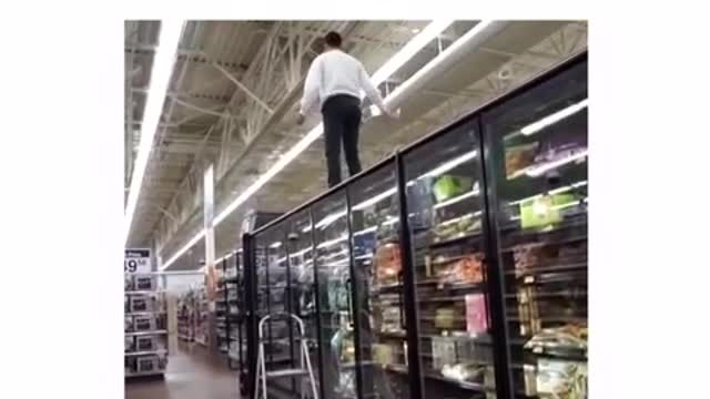 Guy on top of grocery fridges yelling for mom