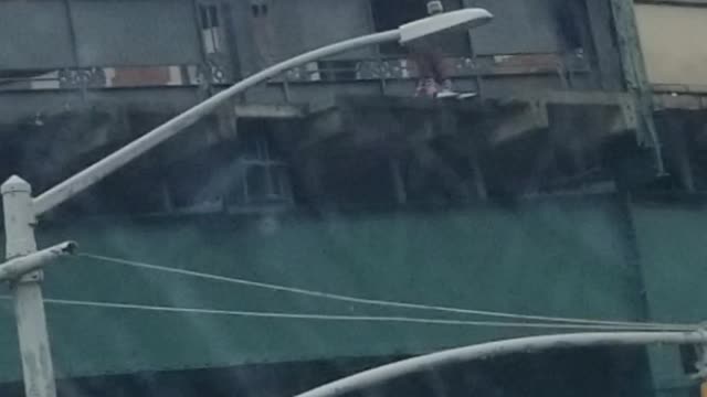 Guy red shirt standing on edge of bridge argument