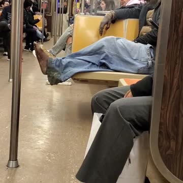 Man smokes and has no shoes on subway train