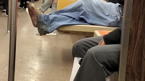 Man smokes and has no shoes on subway train