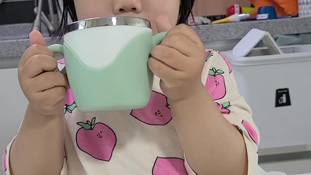 A child uses both hands to drink milk