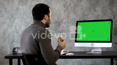 Business man in the office having breakfast, lunch and watching something on the mac, computer