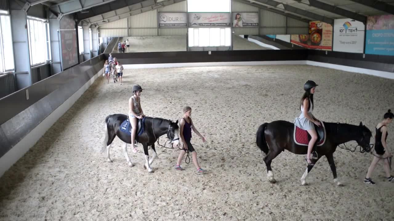 Children are trained to ride horses in the aviary on the sand