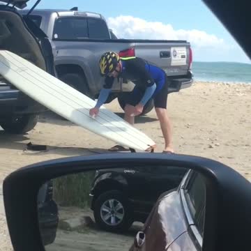 Yellow helmet guy waxes white surfboard out of back car