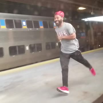 Guy red hat life shirt running next to moving train station platform