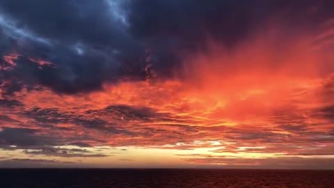 The sunset glow ignites the clouds on the horizon and carries the waves away into the night