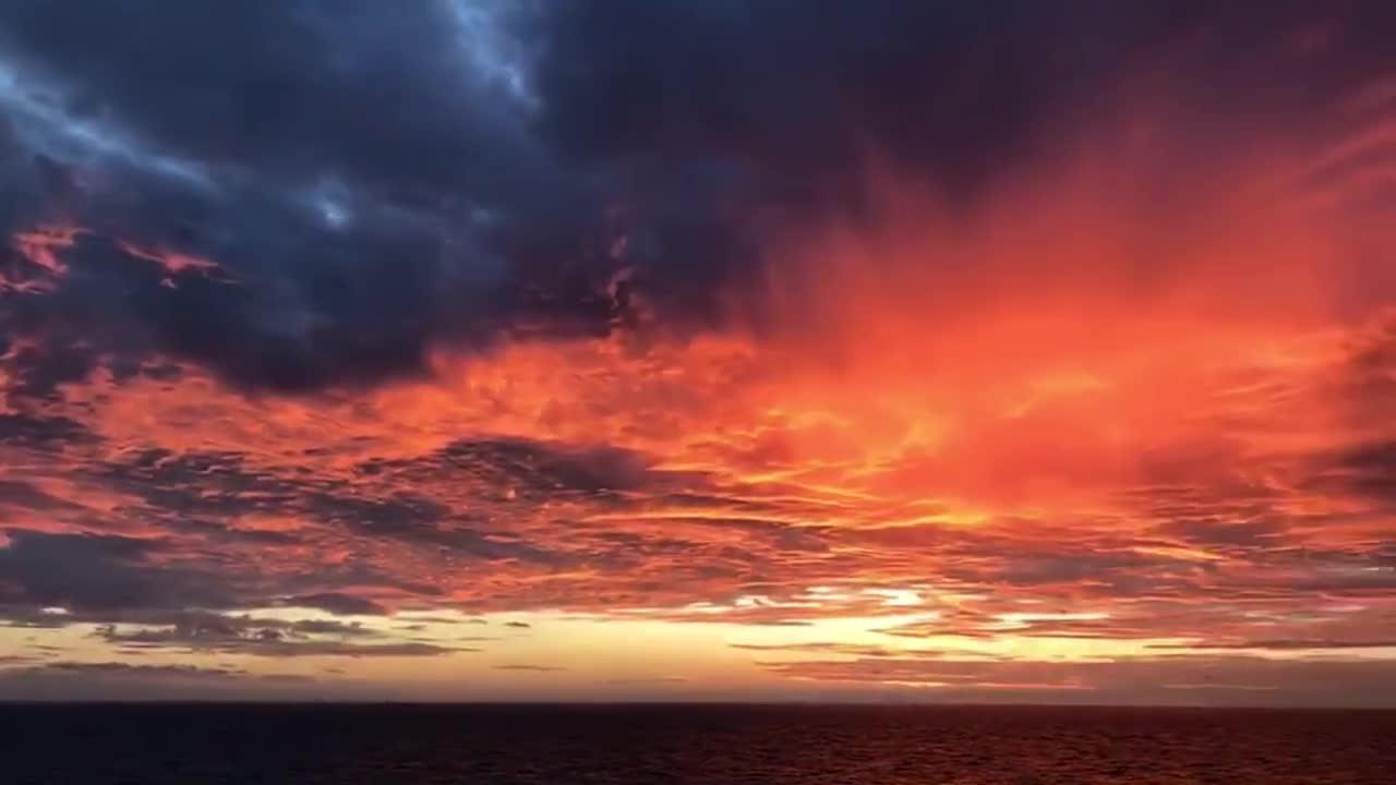 The sunset glow ignites the clouds on the horizon and carries the waves away into the night