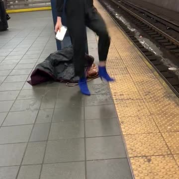 Woman has headphones on and happily dances by herself in subway station
