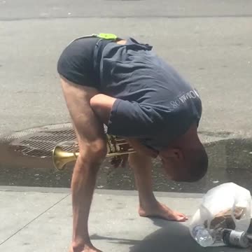 Guy playing trumpet with head between legs