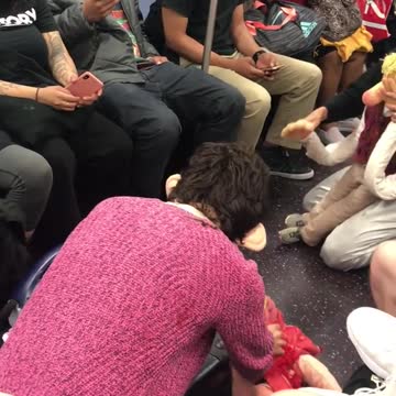 Two people on subway acting out as dolls on subway floor screaming