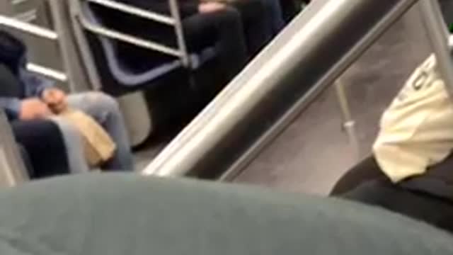 Man has a chucky doll sitting on his lap on subway train