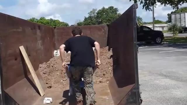 Guy blue wheelbarrow dirt falls in trash can