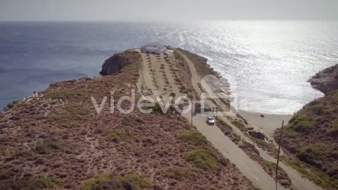 Aerial view of a dirt road with a big house at the end and the sea around