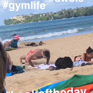 Man in red swim shorts push ups on beach