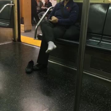 Woman with one shoe off sitting on subway train