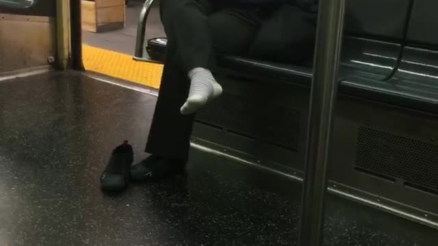 Woman with one shoe off sitting on subway train