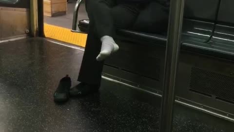 Woman with one shoe off sitting on subway train