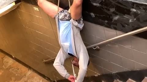 Musician Plays While Hanging Upside Down at Subway Entrance