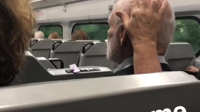 Woman rubs head of old man sitting next to her