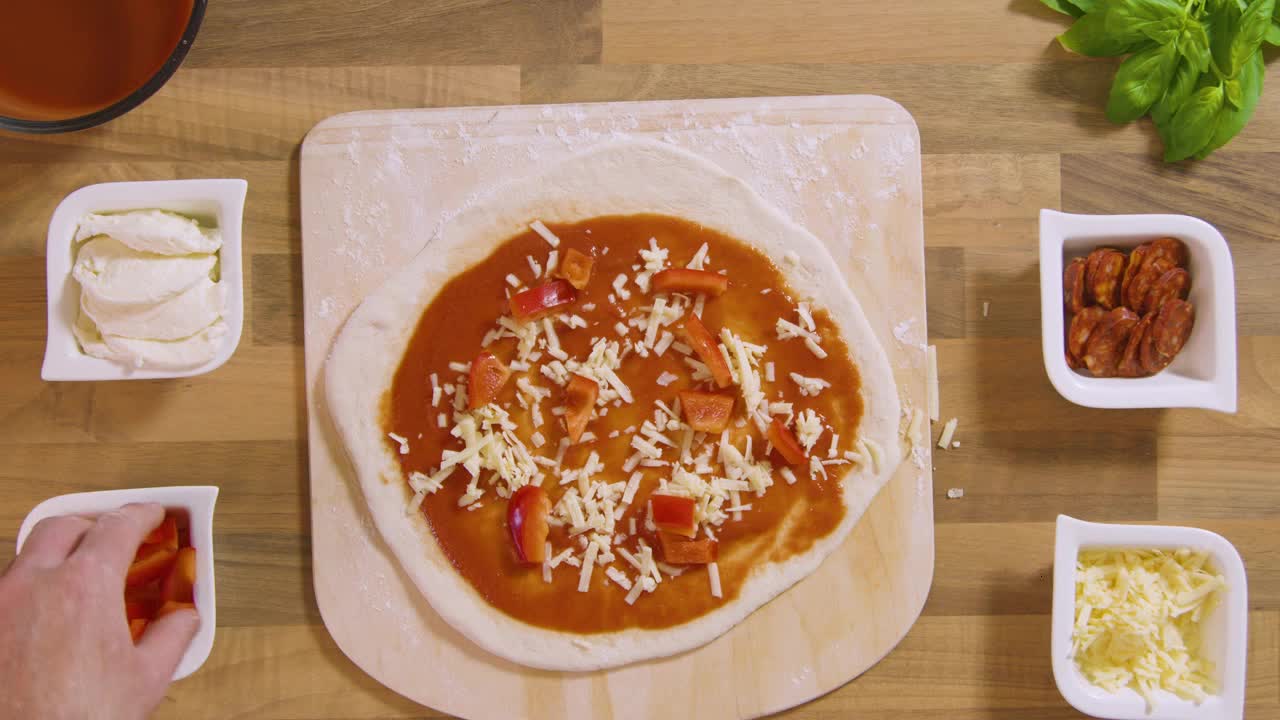 Top View Male Spreads Chopped Red Pepper on Pizza