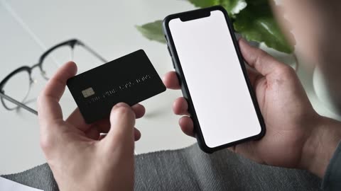 A man using a smartphone while holding a bank card!