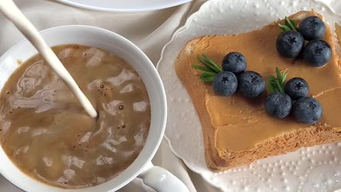 A delicious breakfast that includes coffee with milk next to sandwiches