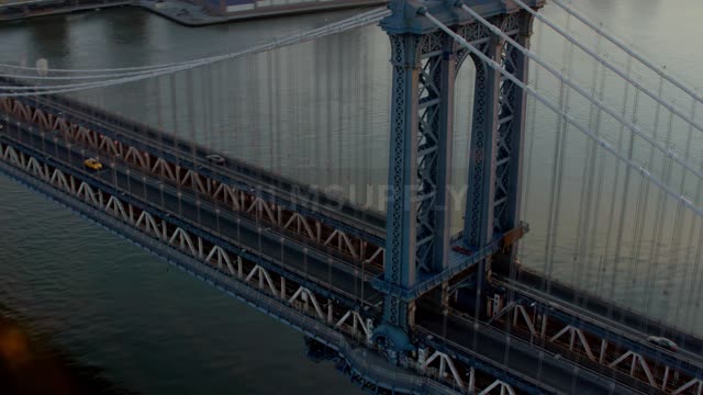 An aerial view of cars driving on a bridge above water is displayed